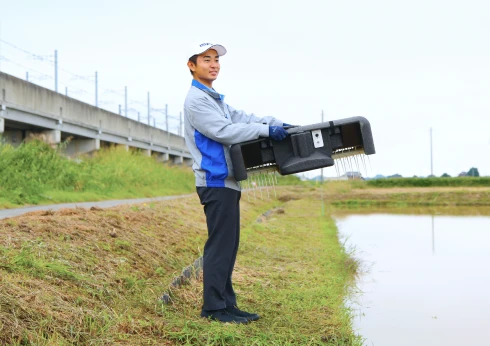 小型・軽量化され、持ち運びが楽になったアイガモロボ2を一人で持ち上げている場面